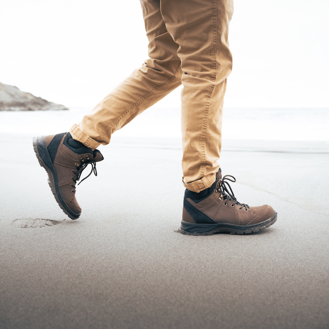 man walking in leather hiking boots with tan pants on the beach to show they are waterproof