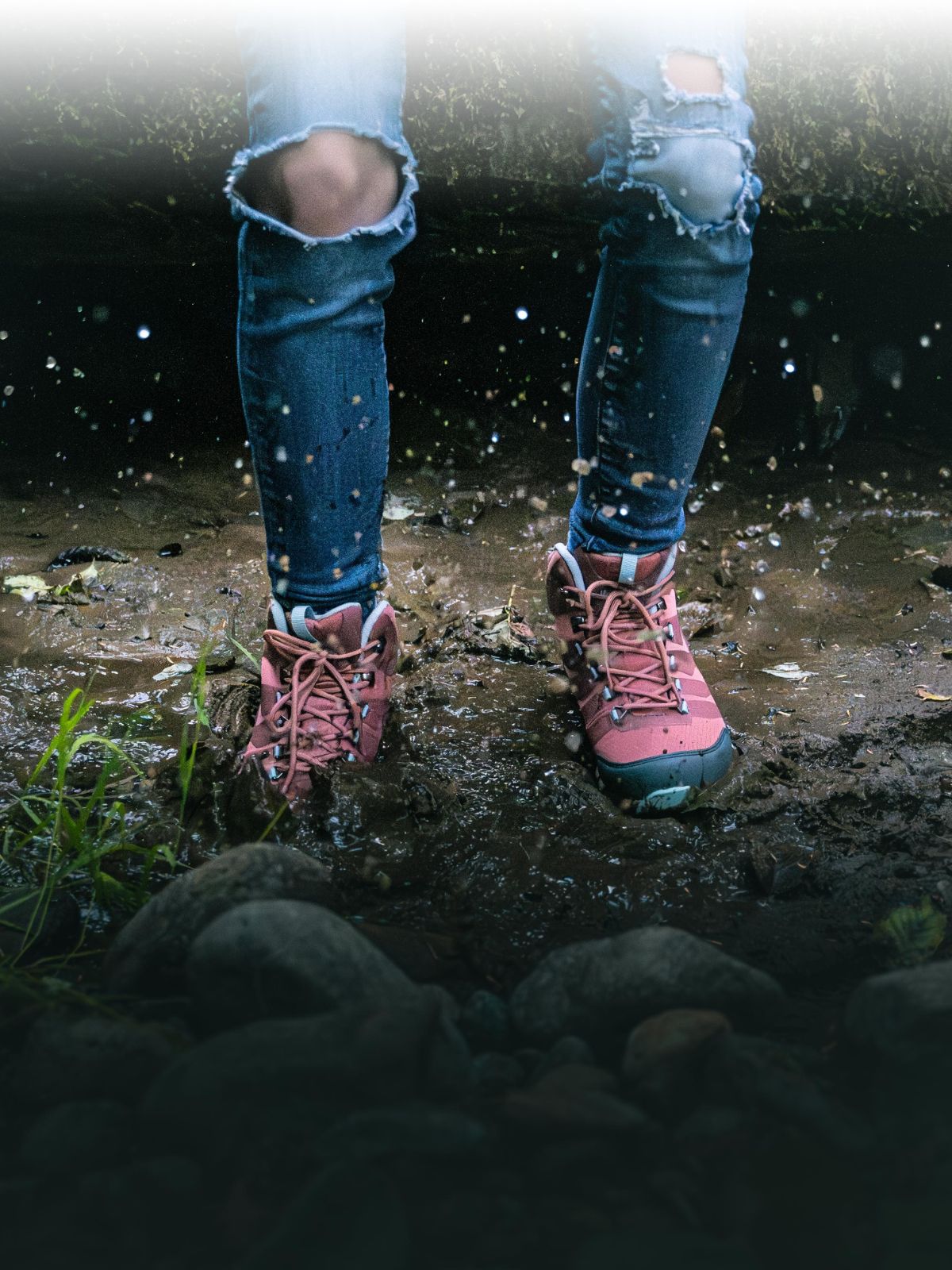 woman jumping in mud puddle with pink hiking boots on that are waterproof and lightweight